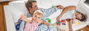 Genitori stanchi e bimba sveglia sul divano: la realtà emotiva del passaggio da coppia a famiglia.