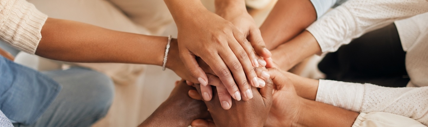 Mani di persone diverse unite in cerchio, a rappresentare la comunità di chi ha frequentato la Formazione in Costellazioni Familiari